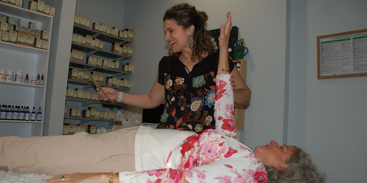 Nicole from Lighthouse Nutrition smiling while performing a muscle testing session on a female clien