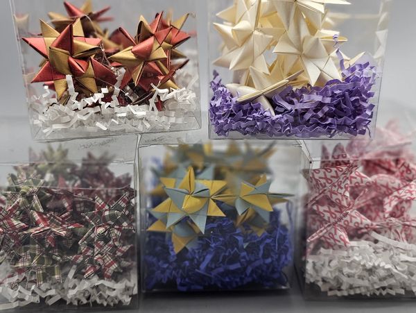 Five clear boxes containing colorful decorative stars with shredded paper.