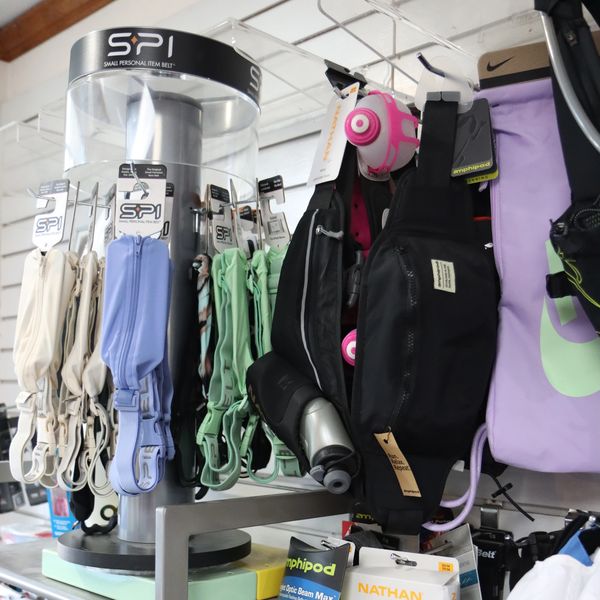 Display of colorful SPI personal item belts and hydration packs in a store.