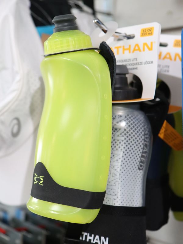 Green and gray Nathan water bottles with black grips hanging on display.