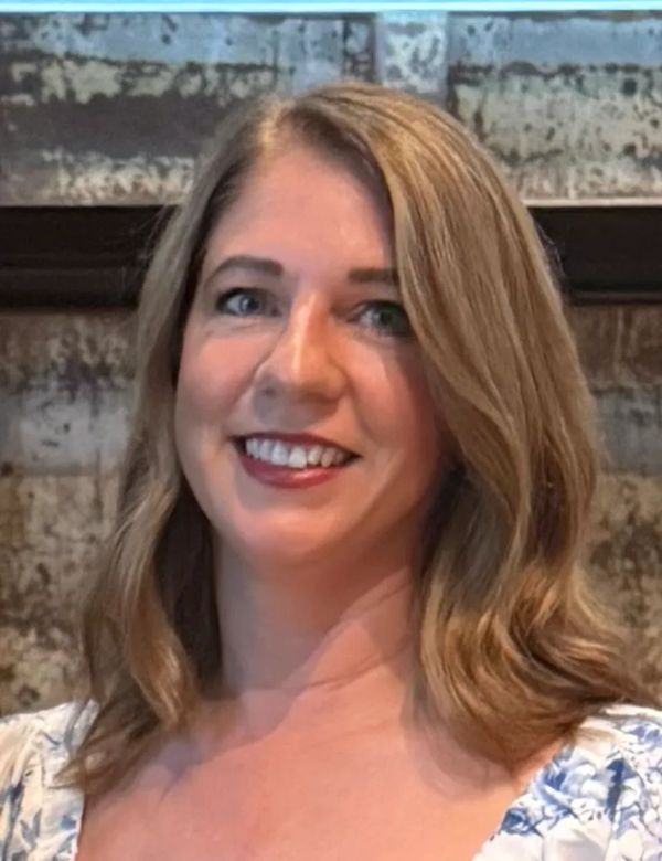Smiling woman with light brown hair indoors.