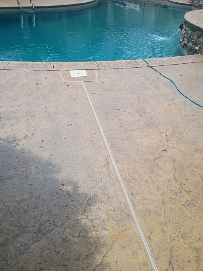 Pool deck with a caulked joint running toward the pool