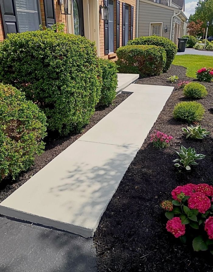 Concrete walkway running through mulched flower beds