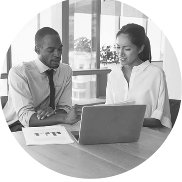 A man and a woman analyzing information from a laptop and some documents. 