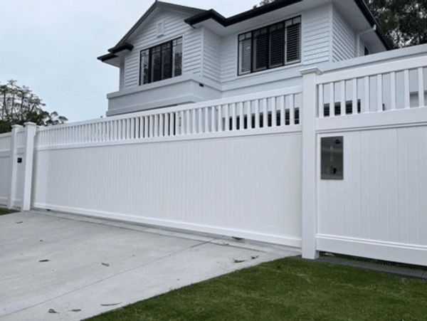 White fence in front of a modern house.
