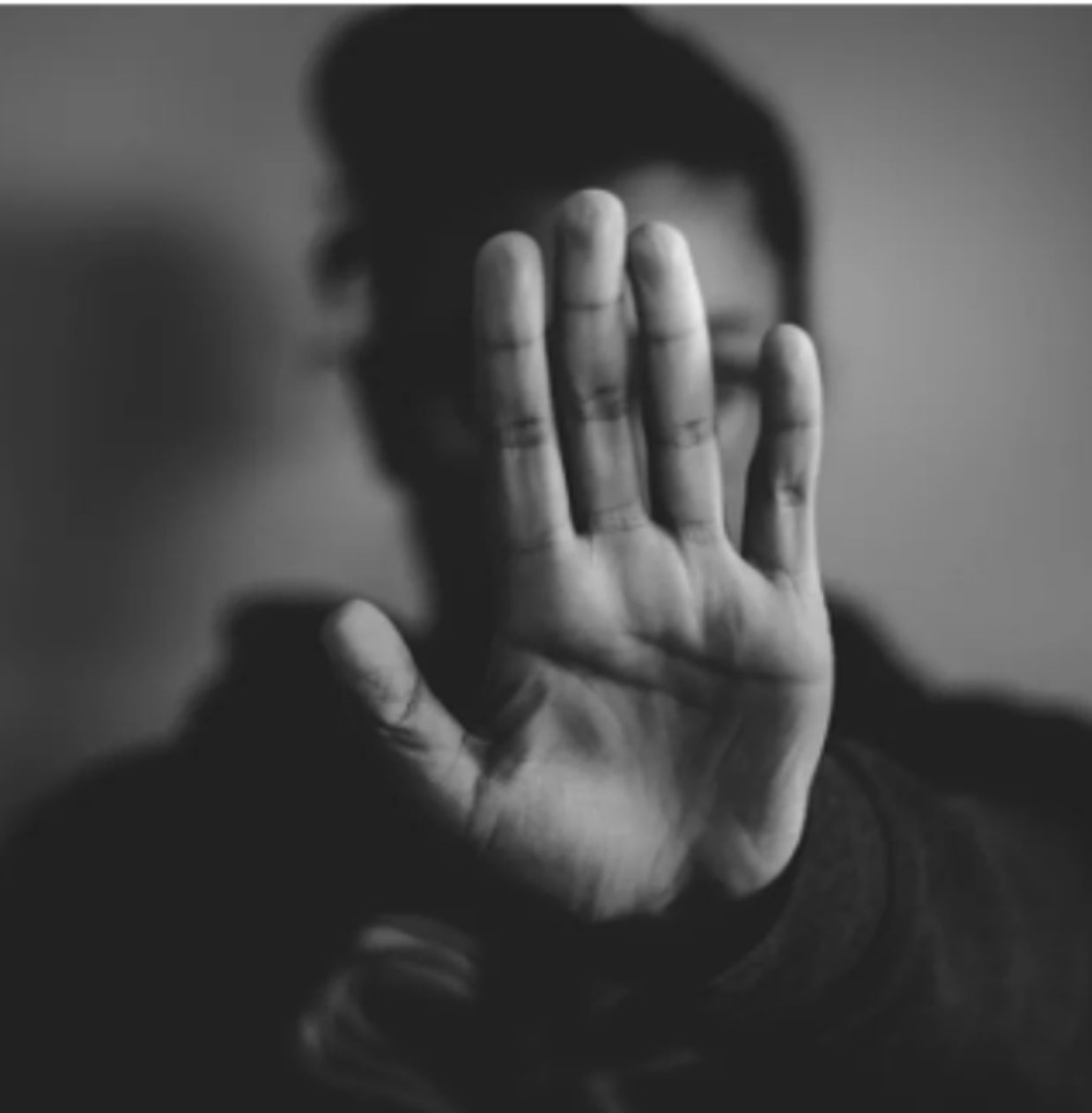 Person showing hand to camera in black and white.