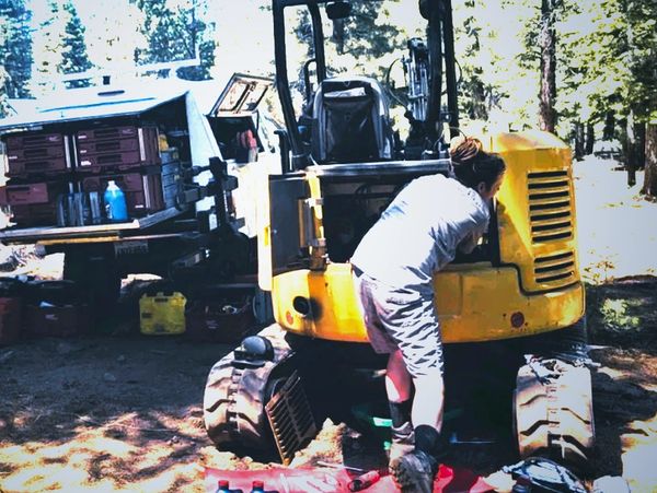 Matt working on heavy machinery that broke down in the woods