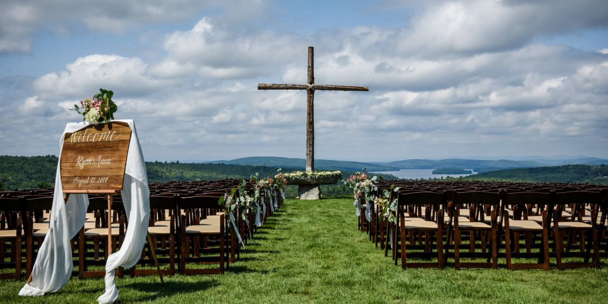 Outdoor wedding setup with wooden cross and chairs.