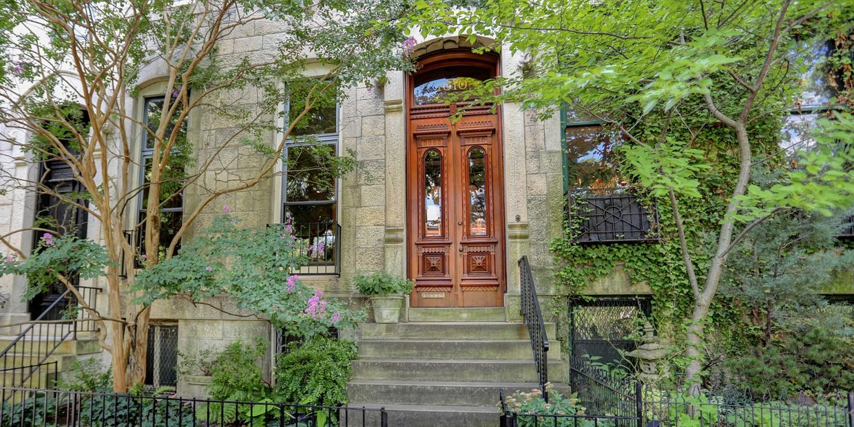 Gorgeous townhouse with exquisite grand brown door and lush greenery in front