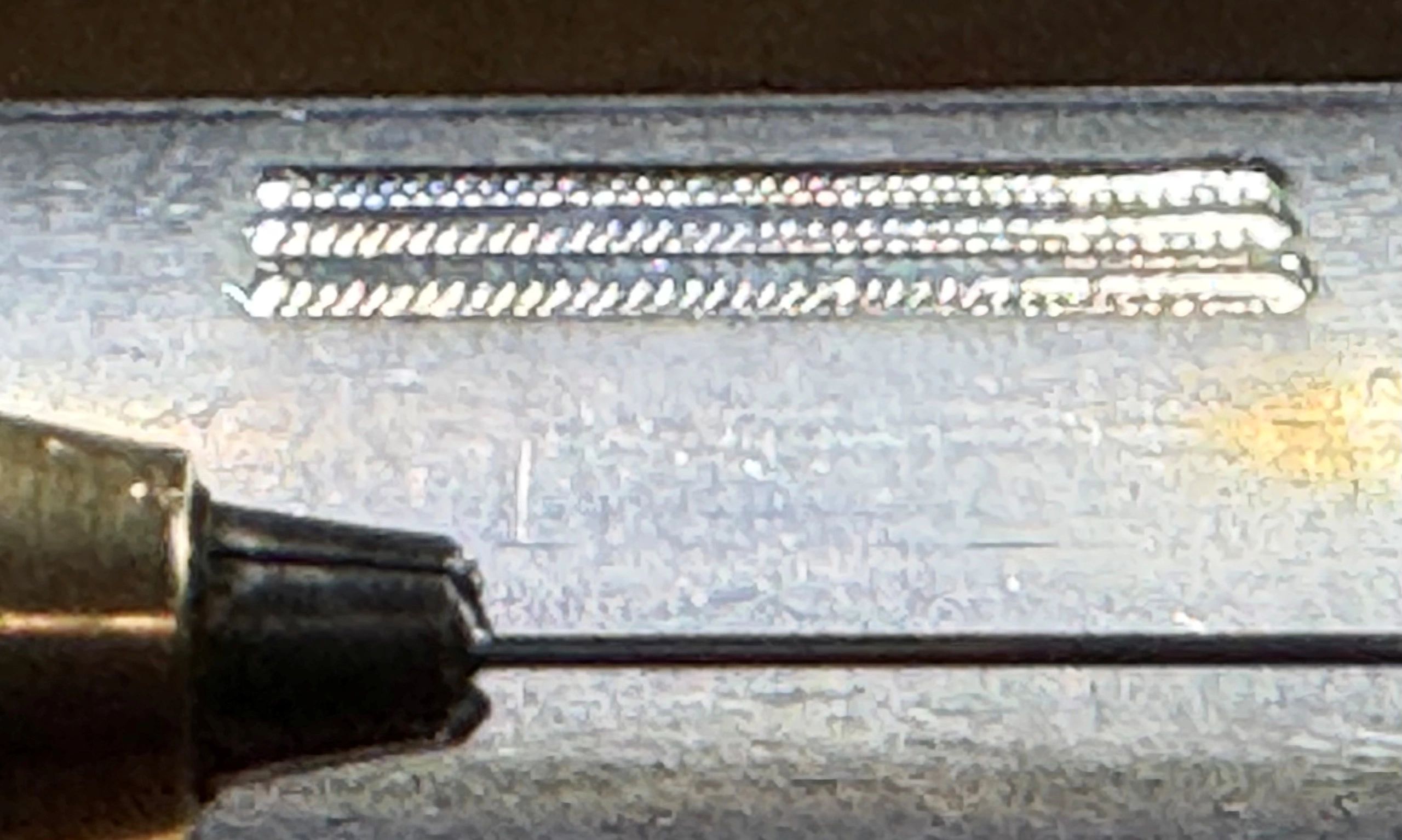 Close-up of a metallic object with engraved text and a bolt.