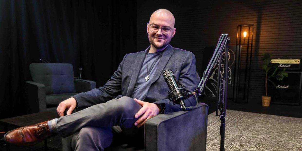 man smiling and  sitting in a chair with a mic