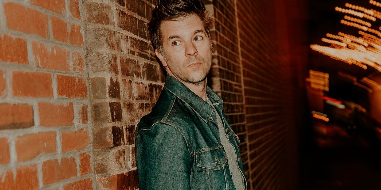 photo of a man standing in fron of a brick wall
