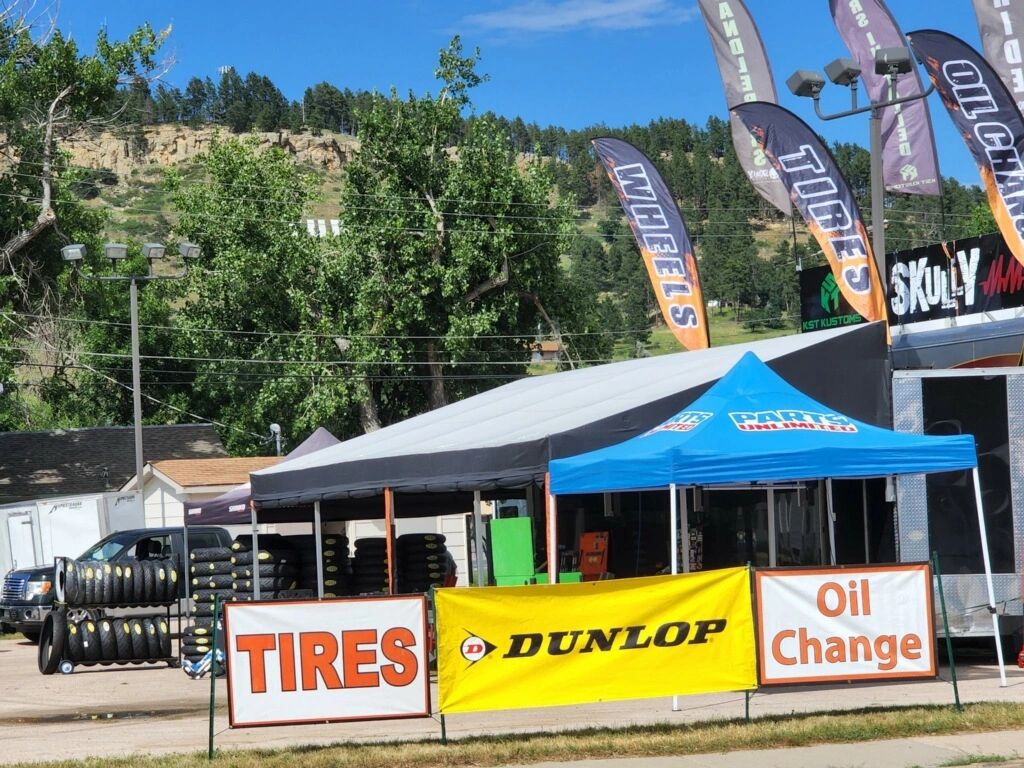 Outdoor tire and oil change service with banners and tents.