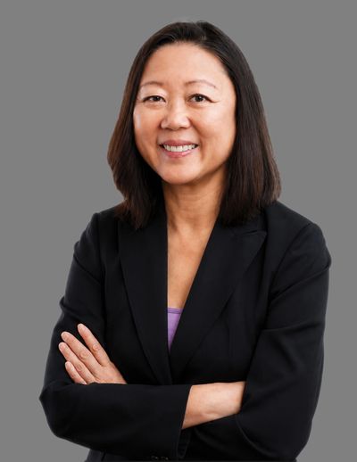 Confident woman in black blazer smiling with arms crossed.