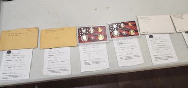 Table with documents, envelopes, and coin sets.