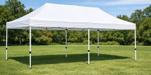 White outdoor canopy tent set up on green grass under blue sky.