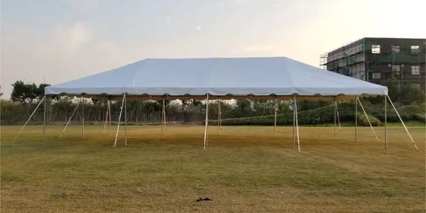 Large white event tent set up on a grassy field under a clear sky.
