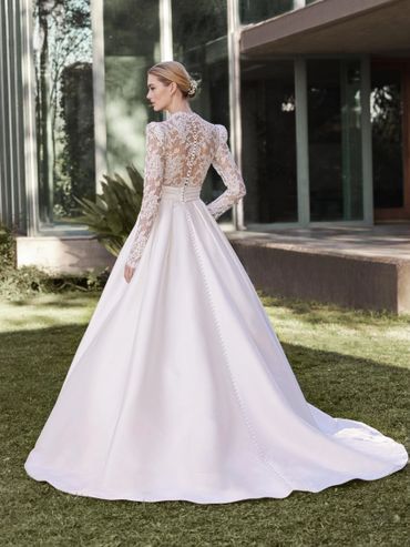 Bride wearing elegant long-sleeve lace wedding dress with a flowing train.