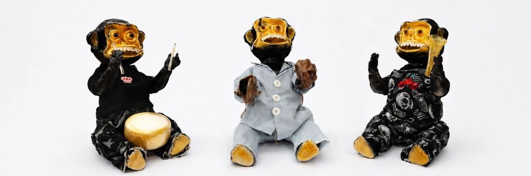 Three monkey figurines dressed in different outfits playing instruments.