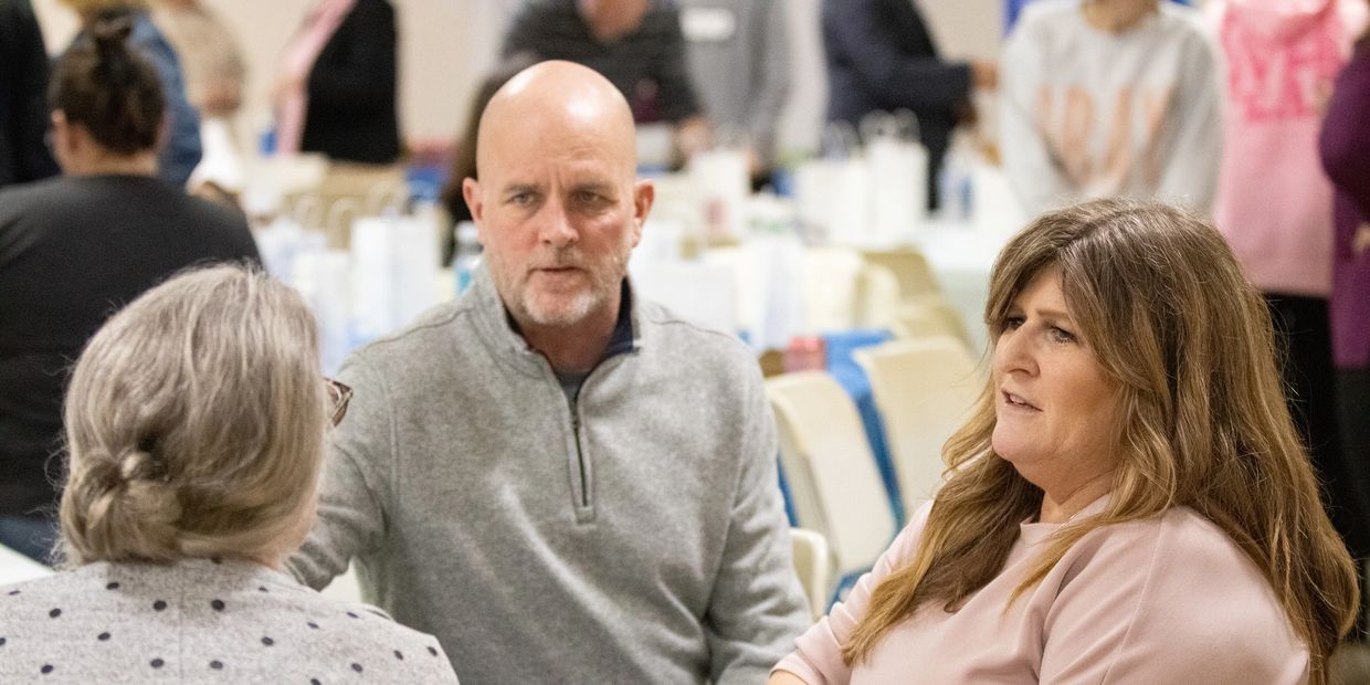 Three adults engaged in a serious conversation at a gathering.