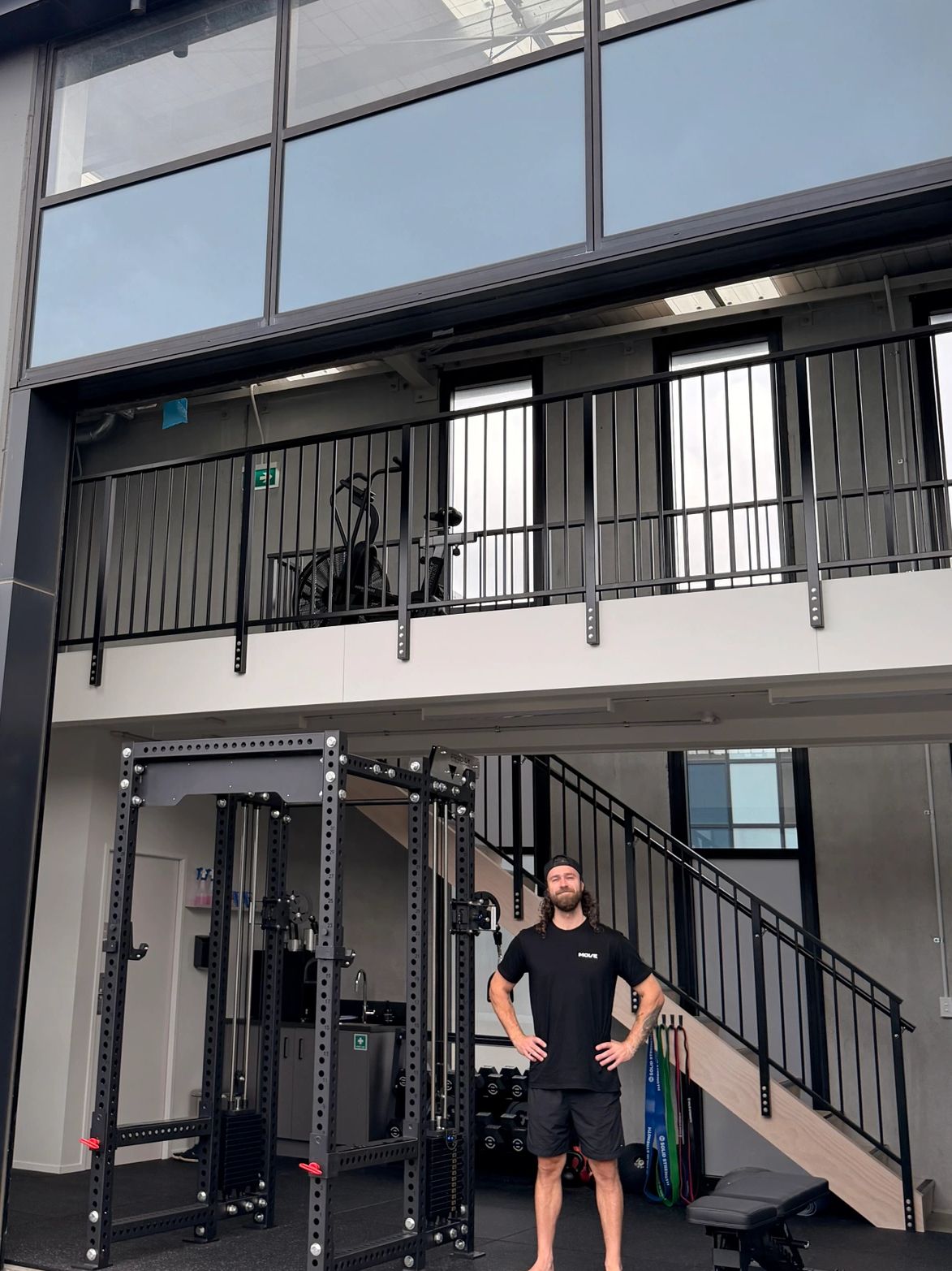 Man standing confidently in a modern home gym with workout equipment.