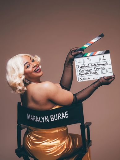 Woman in golden dress holding a clapperboard.
