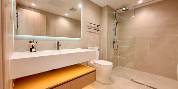 Modern bathroom with beige tiles, glass shower, and wooden vanity.