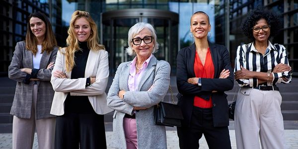 Confident diverse businesswomen standing together outside an office building.