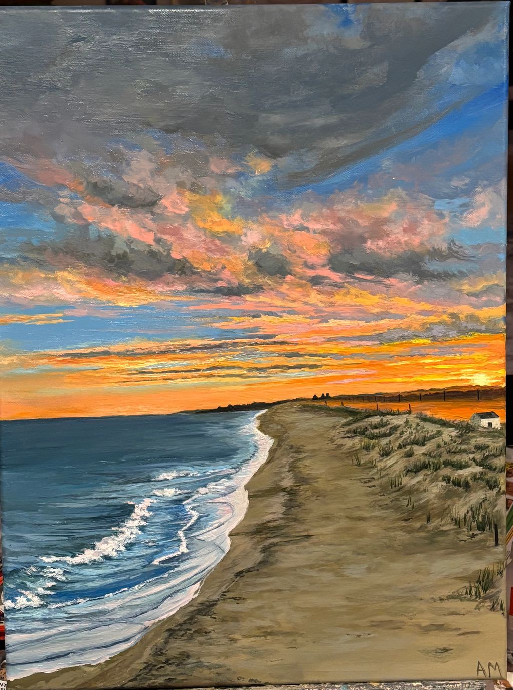 A vibrant sunset over a calm beach with waves gently rolling in.