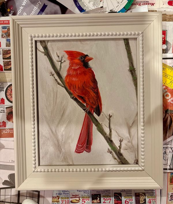 Painting of a vibrant red cardinal perched on a branch in a white decorative frame.