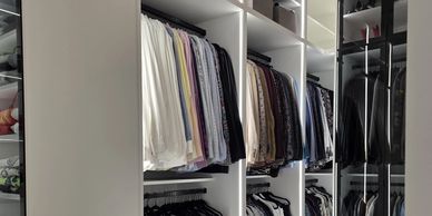 Organized wardrobe with hanging clothes.
