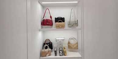 Display of handbags and accessories on white shelves.