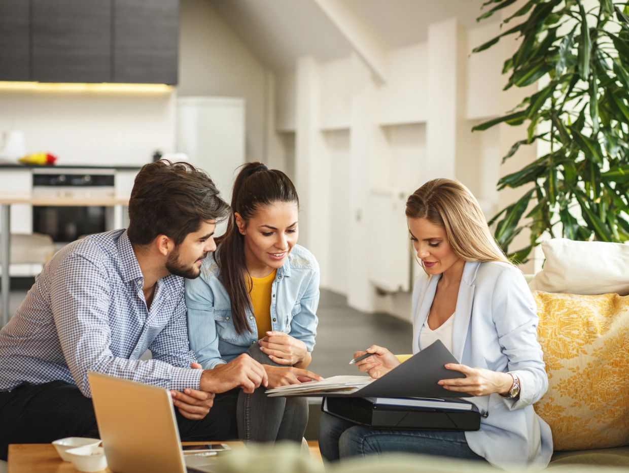 Couple consulting a professional woman at home with documents.