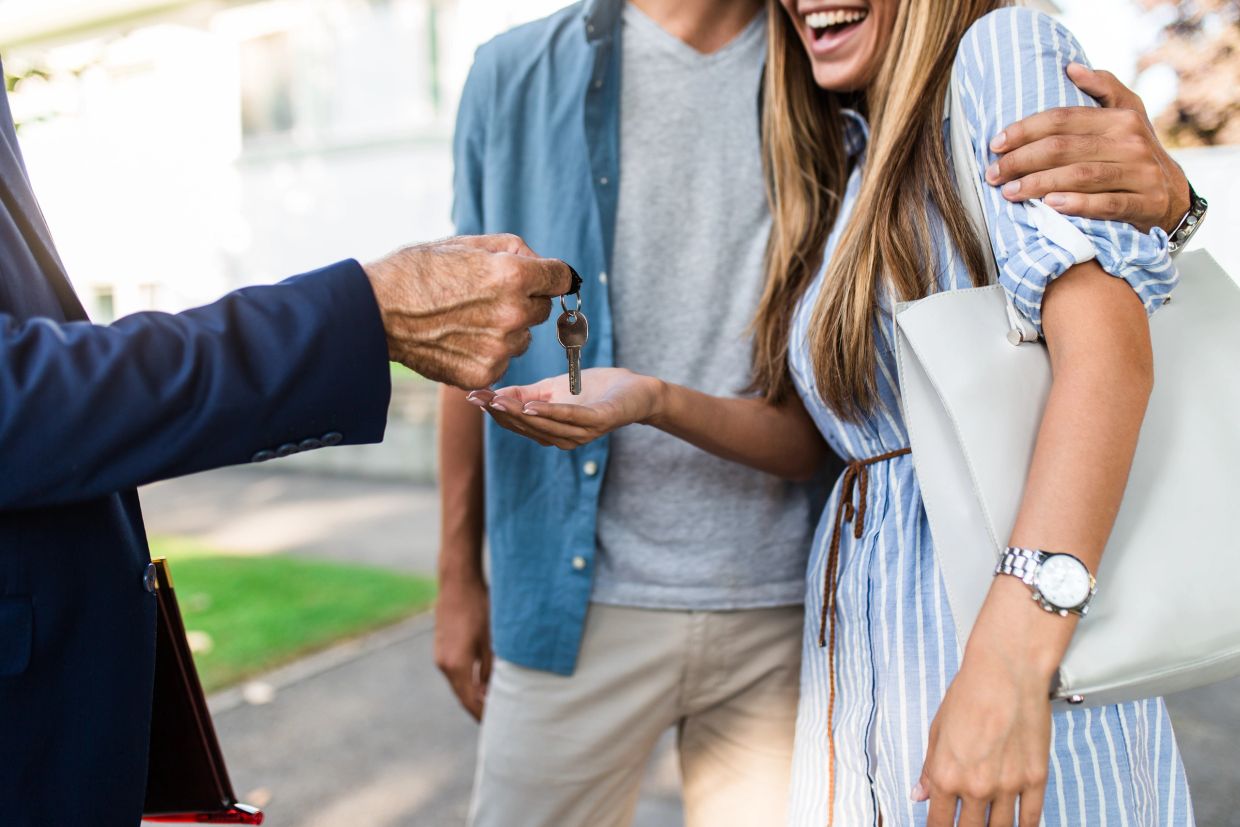 Couple happily receiving house keys from agent.