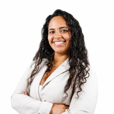 Confident woman with curly hair smiling, arms crossed.