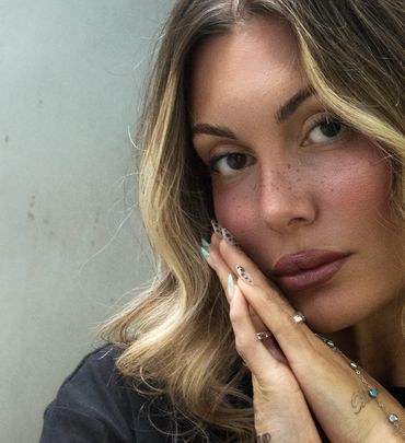 Close-up of woman with wavy hair and detailed nails.