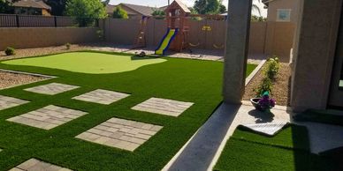 Backyard with green artificial turf and a children's slide.