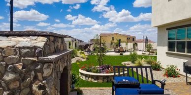 Sunny backyard with stone fireplace and seating area.