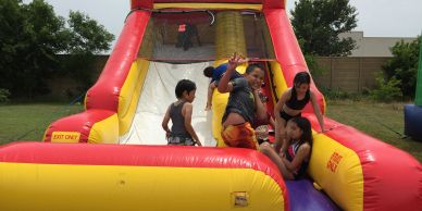 Kids enjoying an inflatable water slide on a sunny day.