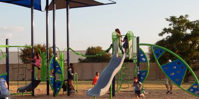 Children playing on a colorful playground with slides and climbing structures.