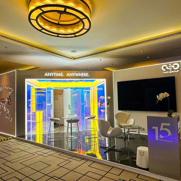 Modern exhibition booth with colorful lighting and sleek furniture celebrating 15th anniversary.
