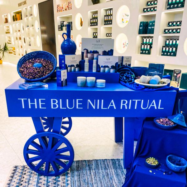 A vibrant blue cart display showcases skincare products labeled 'The Blue Nila Ritual.'