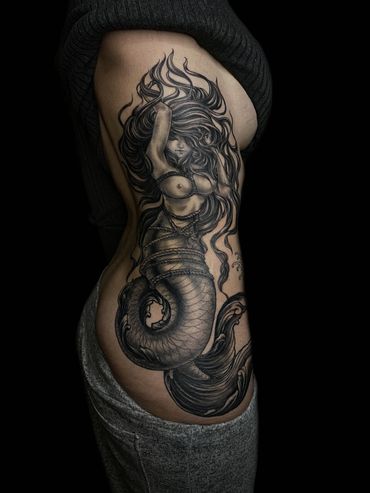 A mermaid tattoo on a person's side torso