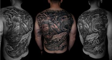 A back tattoo of God looking at a ship on the sea