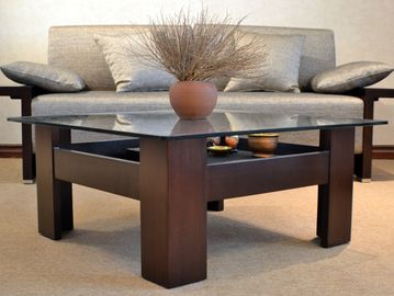 Modern glass coffee table with wooden legs in a living room.