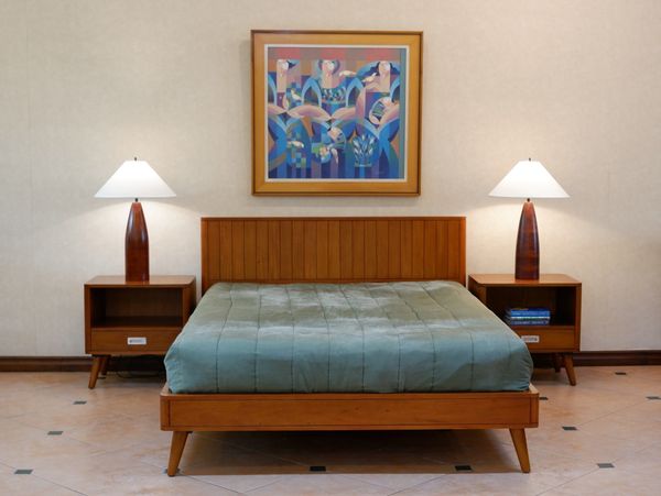 Minimalist bedroom with wooden bed and nightstands, modern lamps, and colorful abstract artwork.