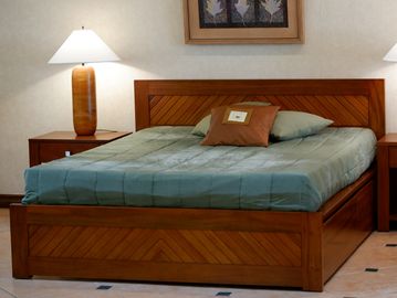 Wooden bed with teal bedding and bedside lamps in a cozy room.