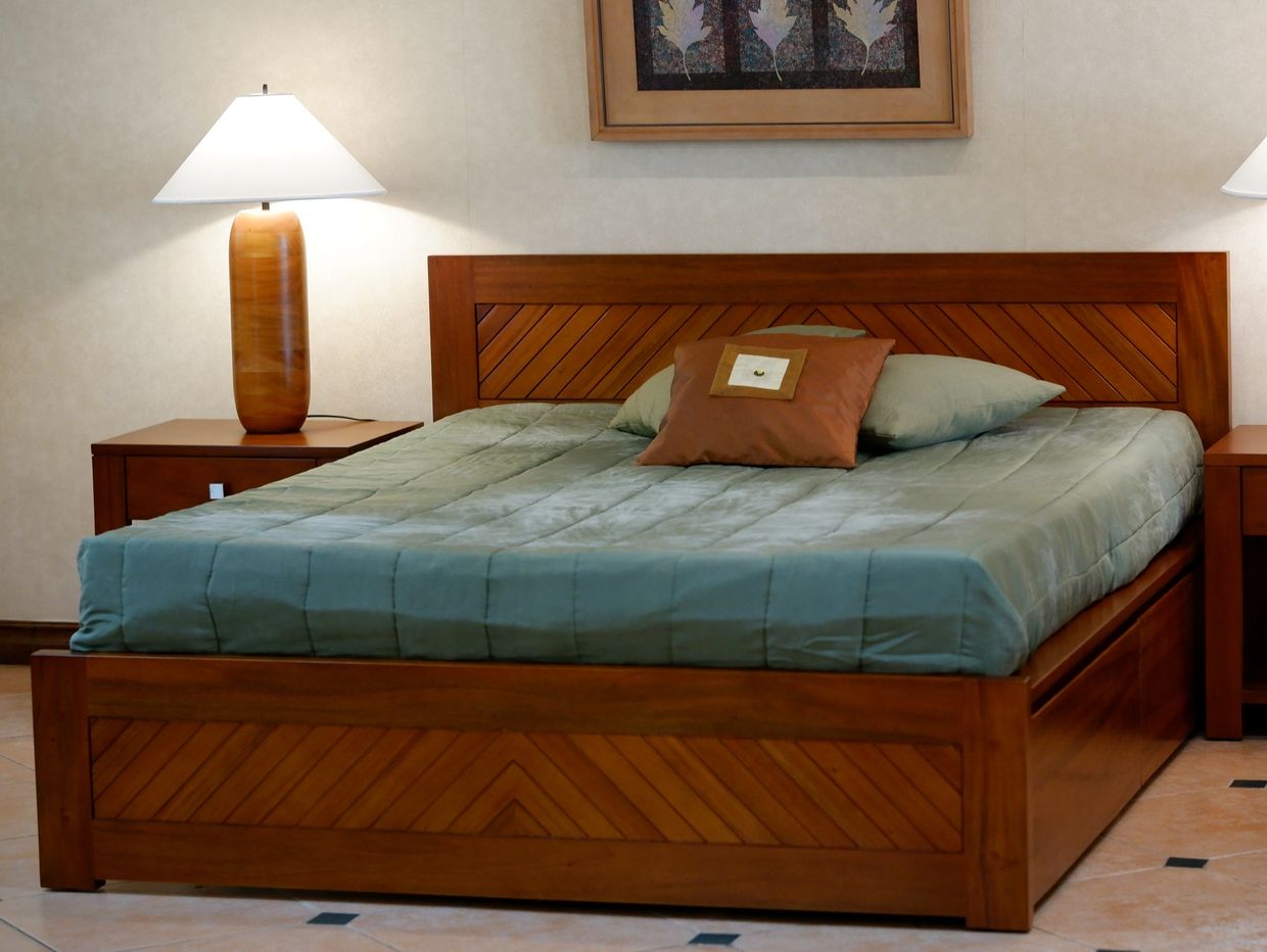Wooden bed with green bedding and brown pillows in a cozy bedroom.