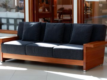 Modern wooden sofa with dark cushions in a bright room.