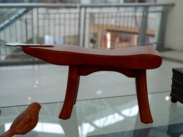A small wooden stool with curved legs on a glass table.